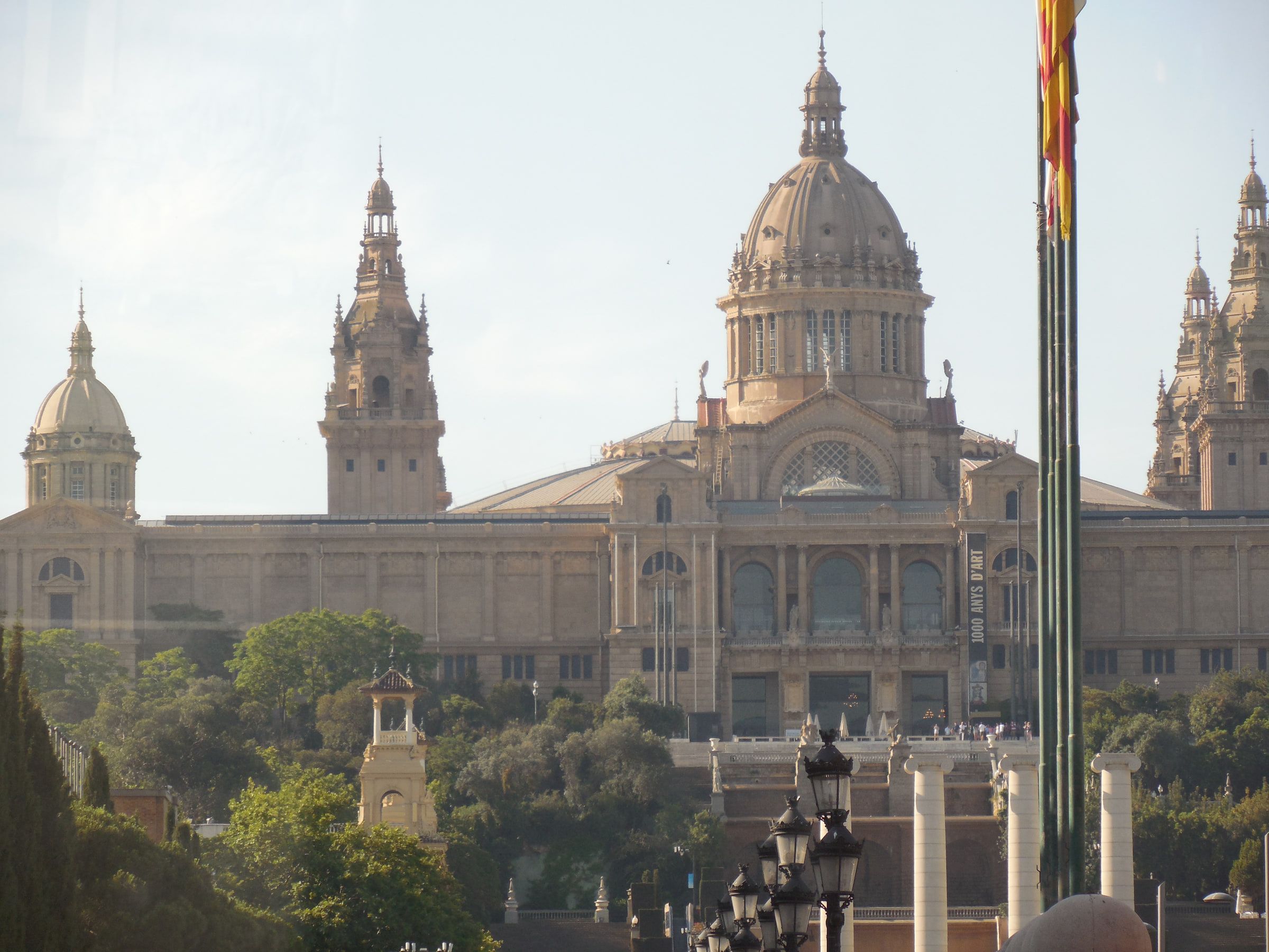 A domed neoclassical palace with corner towers standing on a wooded hill, flagpoles in front of it