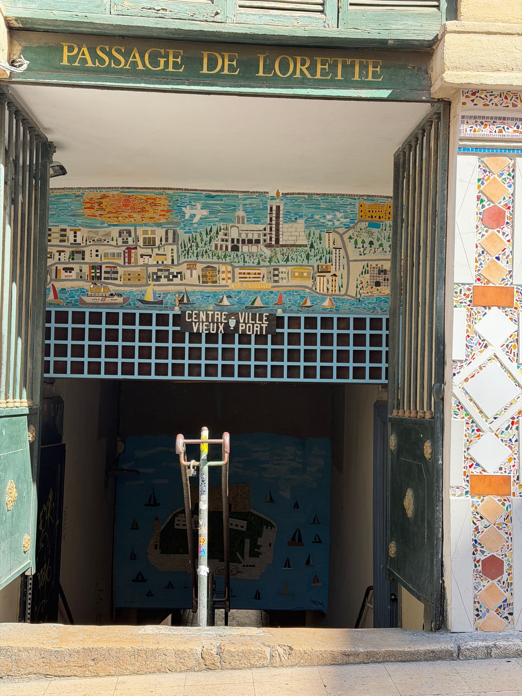 A tiled entrance under a gilded sign reading Passage de Lorette, with a mosaic panel of a city and its harbour above the doorway