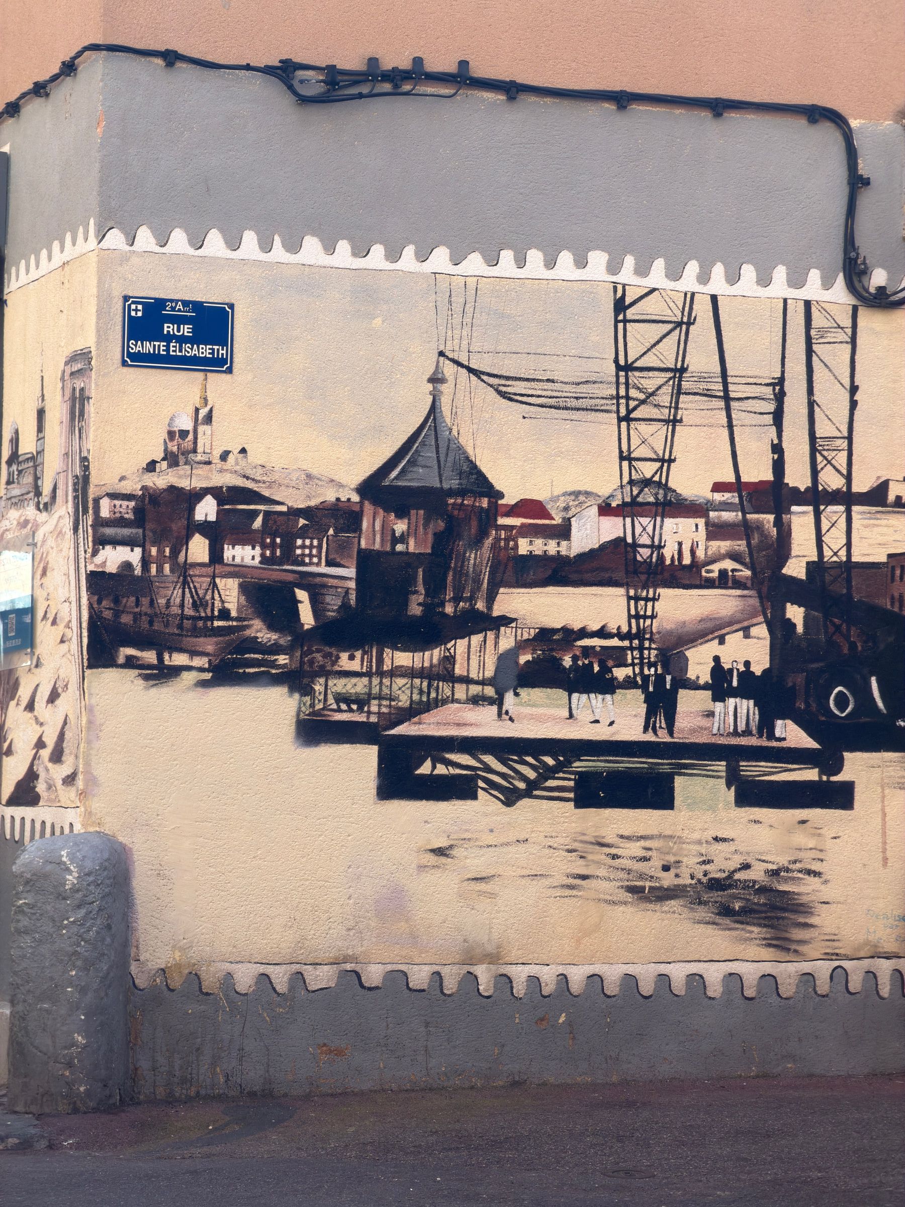 A large sepia mural of an old working harbour with cranes and sailing ships, painted across a wall beneath a blue street sign