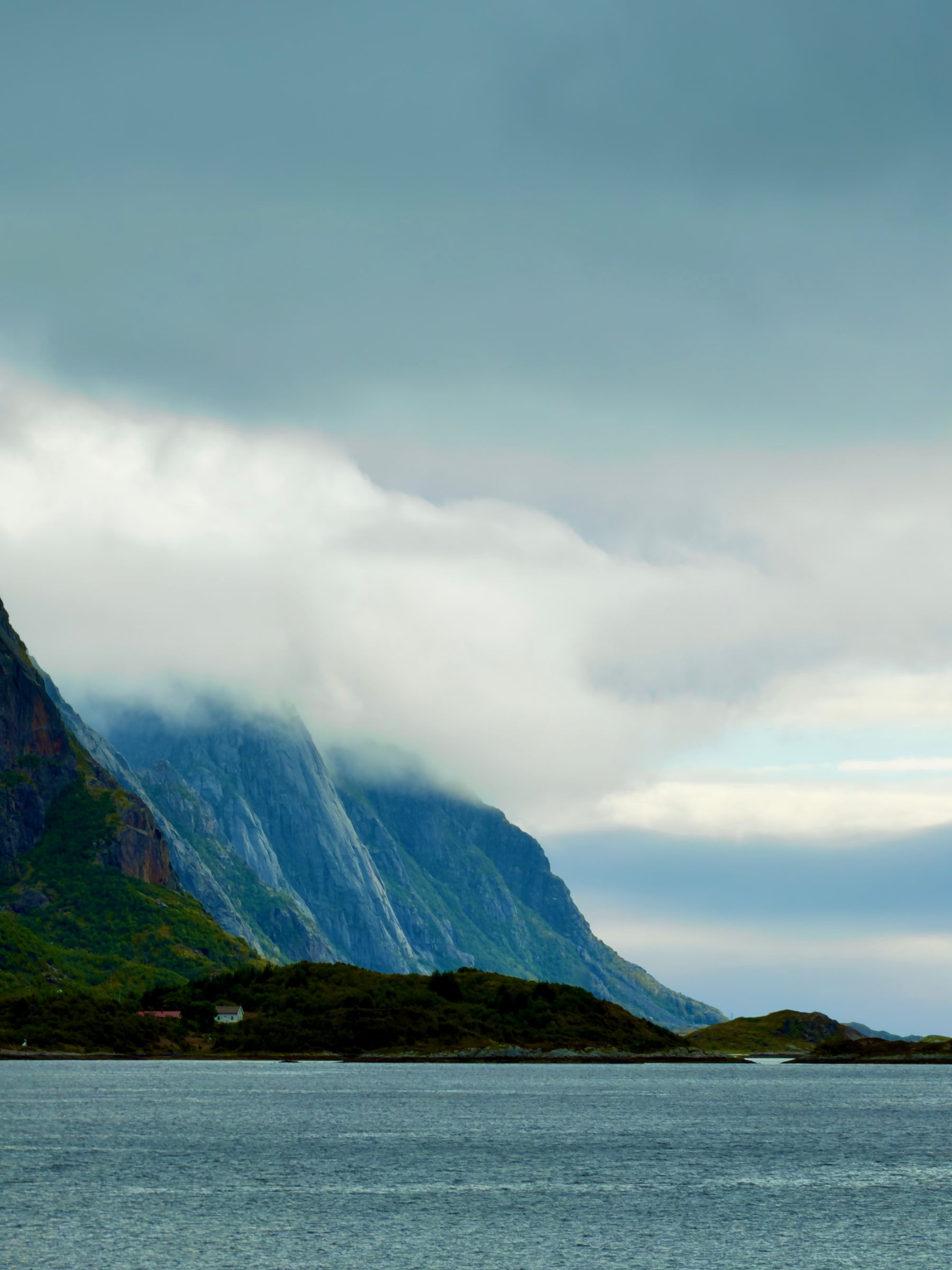A steep headland with cloud pouring over its ridge, dark sea in the foreground