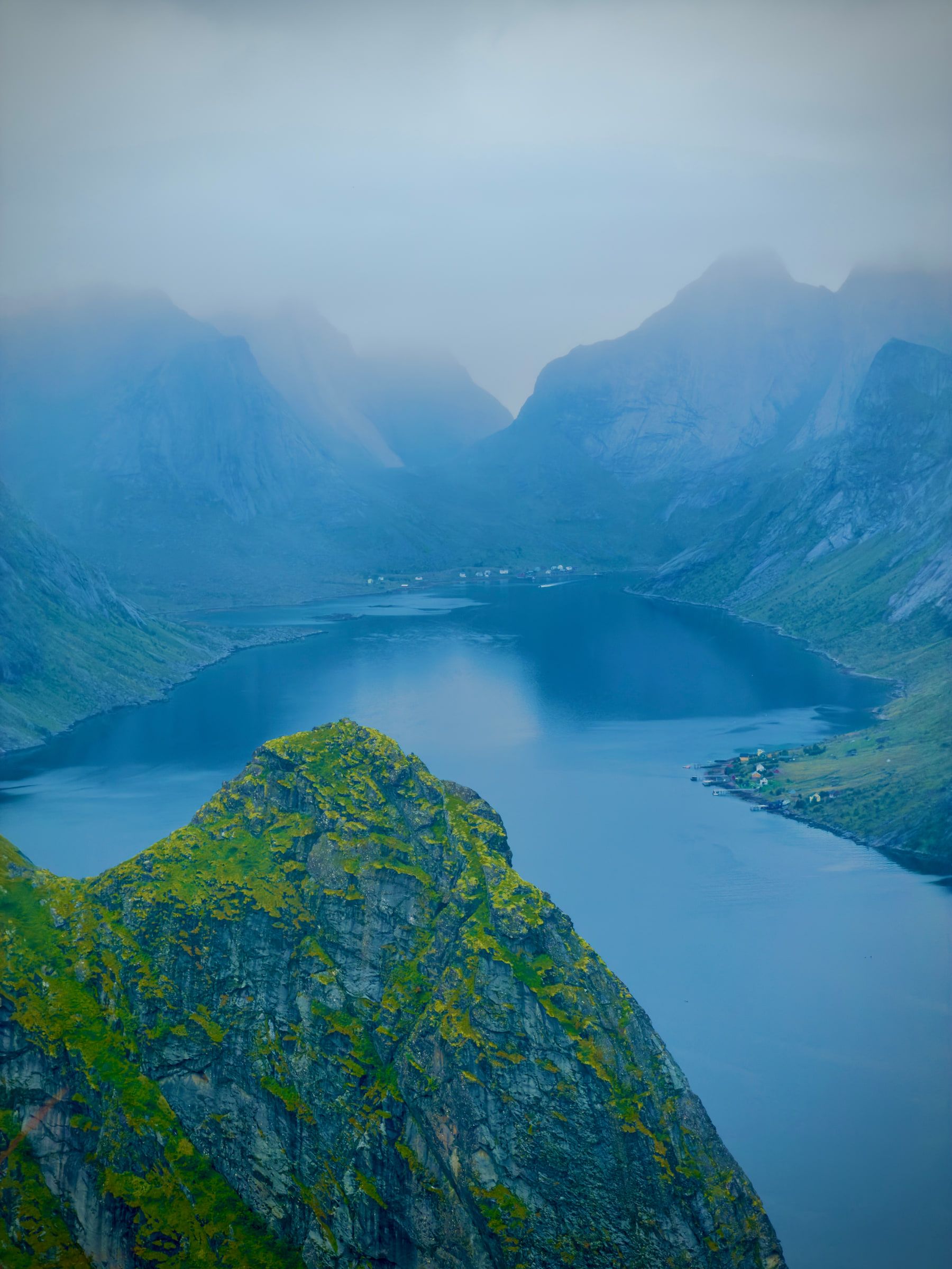 A high view down a long fjord between steep mountains, the far end lost in low cloud