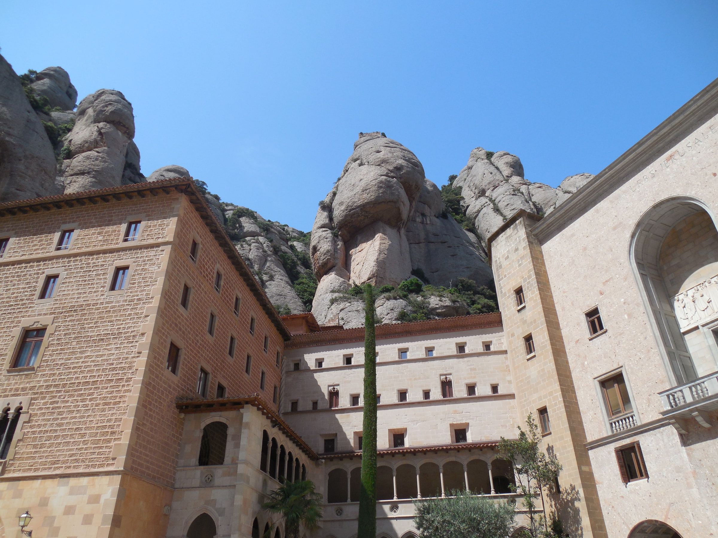Monastery buildings set beneath rounded rock pinnacles under a clear sky