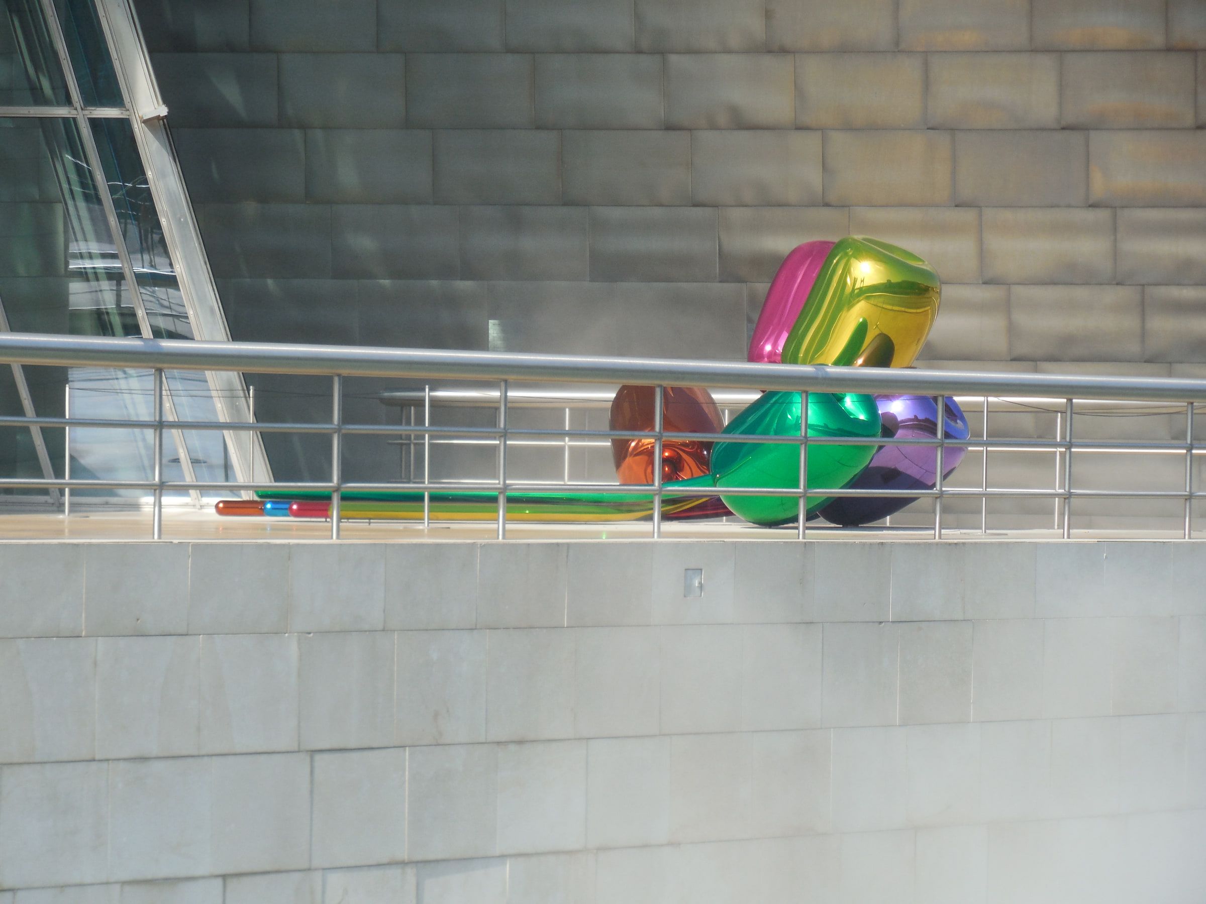A cluster of large glossy multicoloured balloon-like flower sculptures on a stone terrace