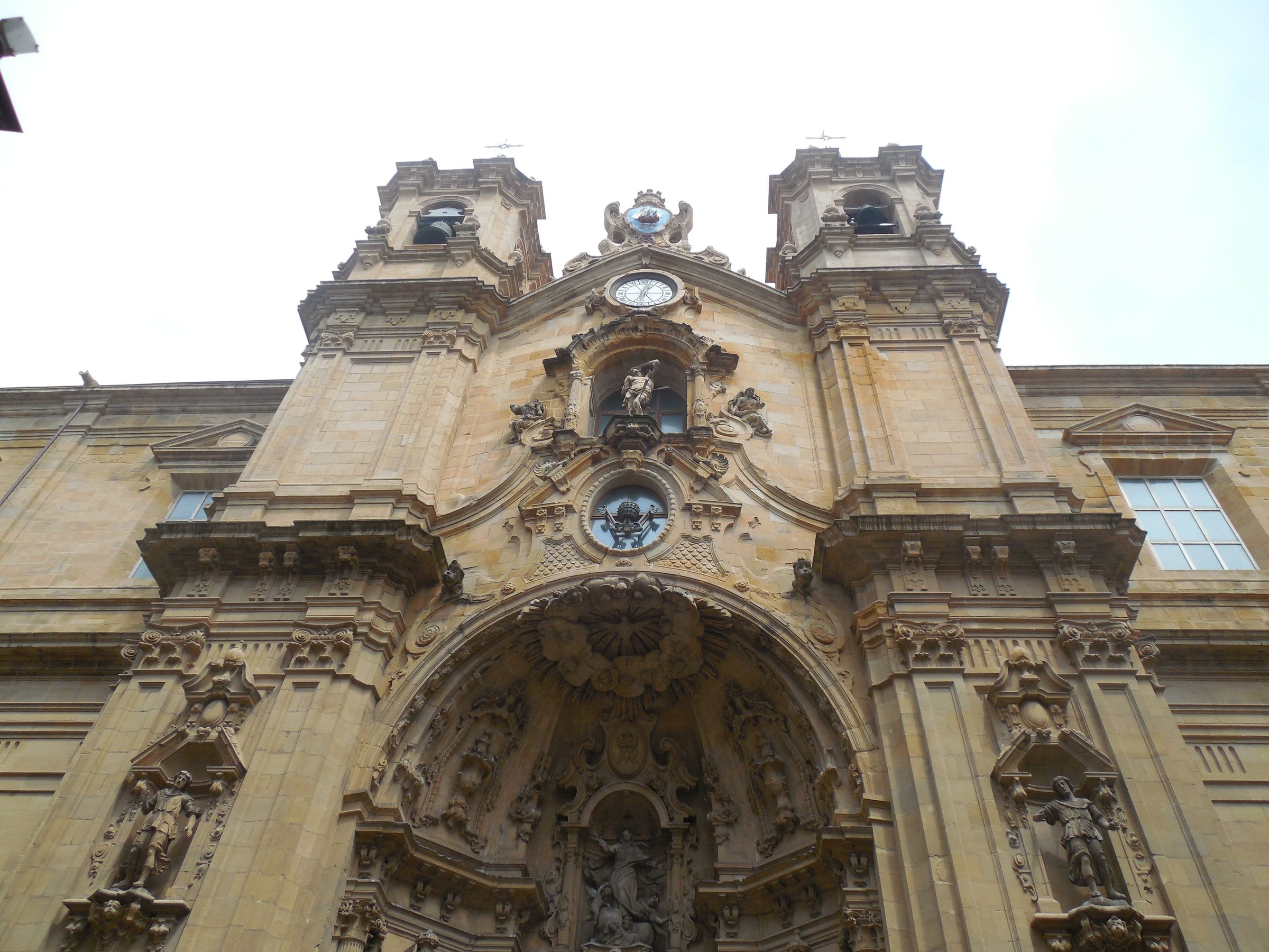 An ornate baroque church facade with twin bell towers, photographed from directly below