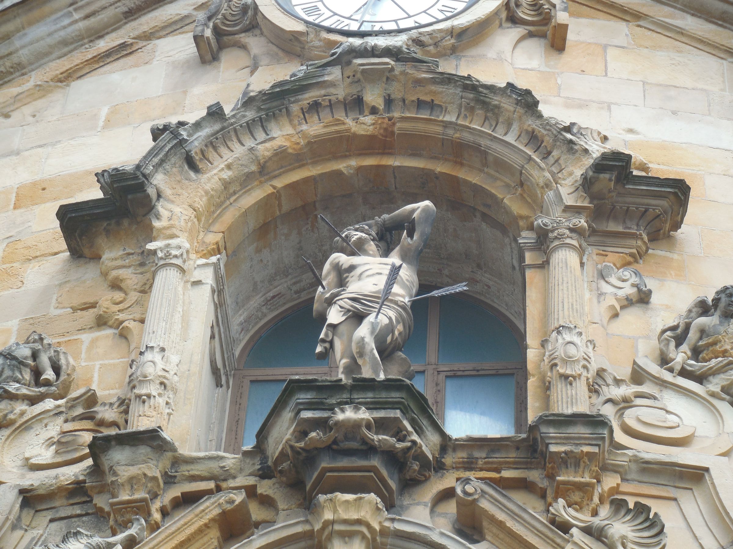 A carved church portal with a statue of a bound figure pierced by arrows above the door