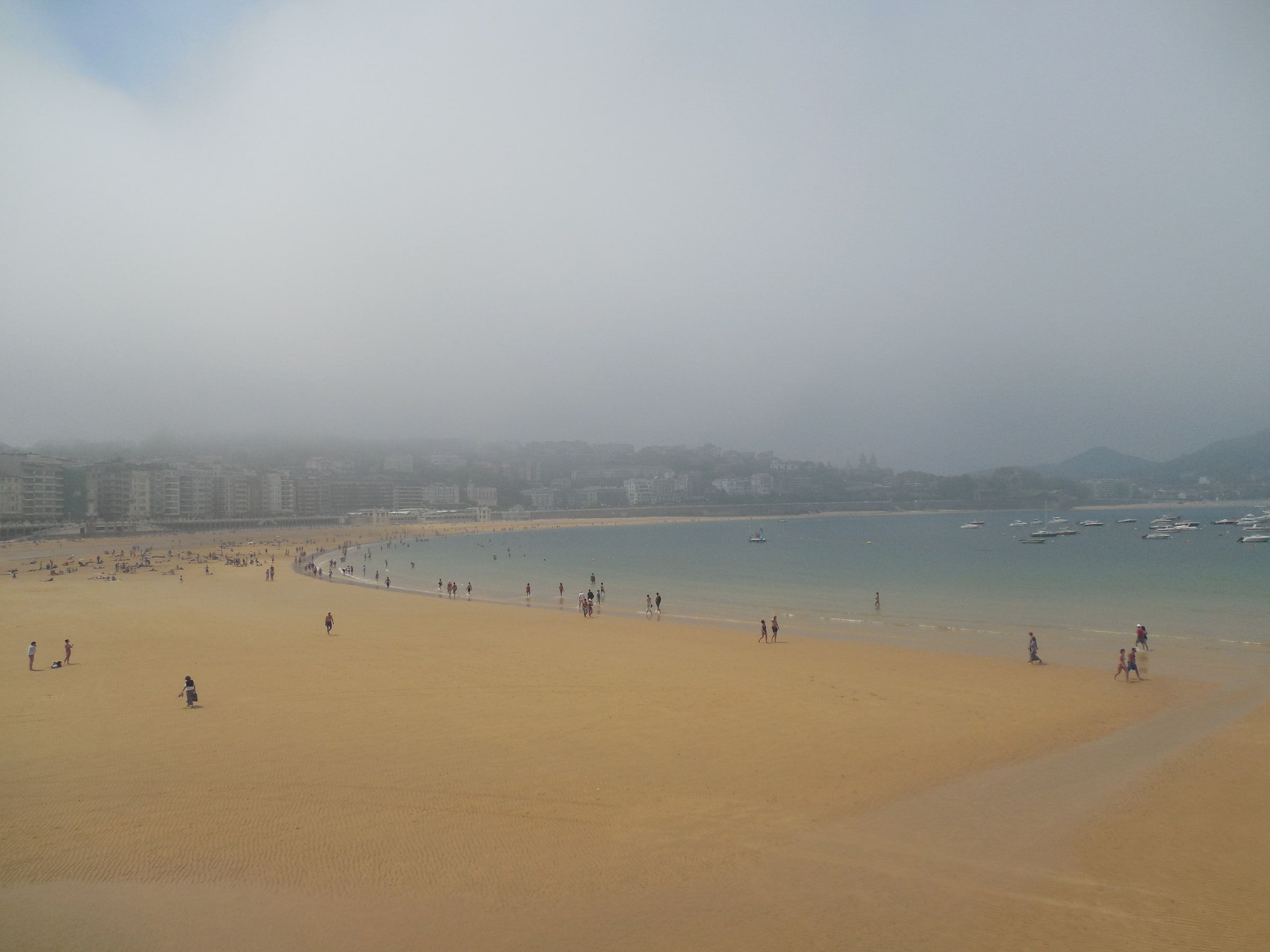 A wide sandy beach and bay in thick mist, the far shore barely visible