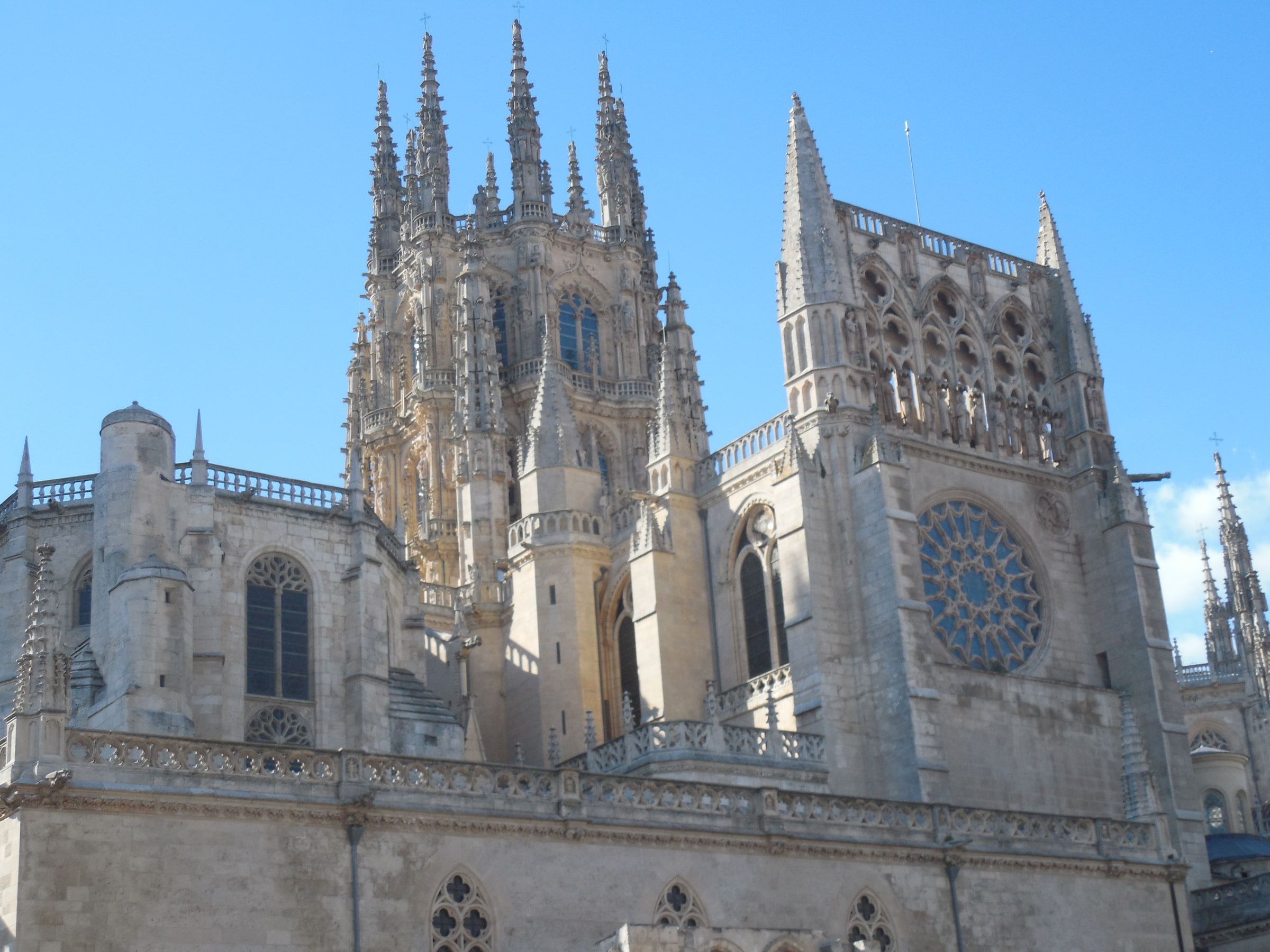 The pierced stone spires and rose window of a Gothic cathedral against a blue sky