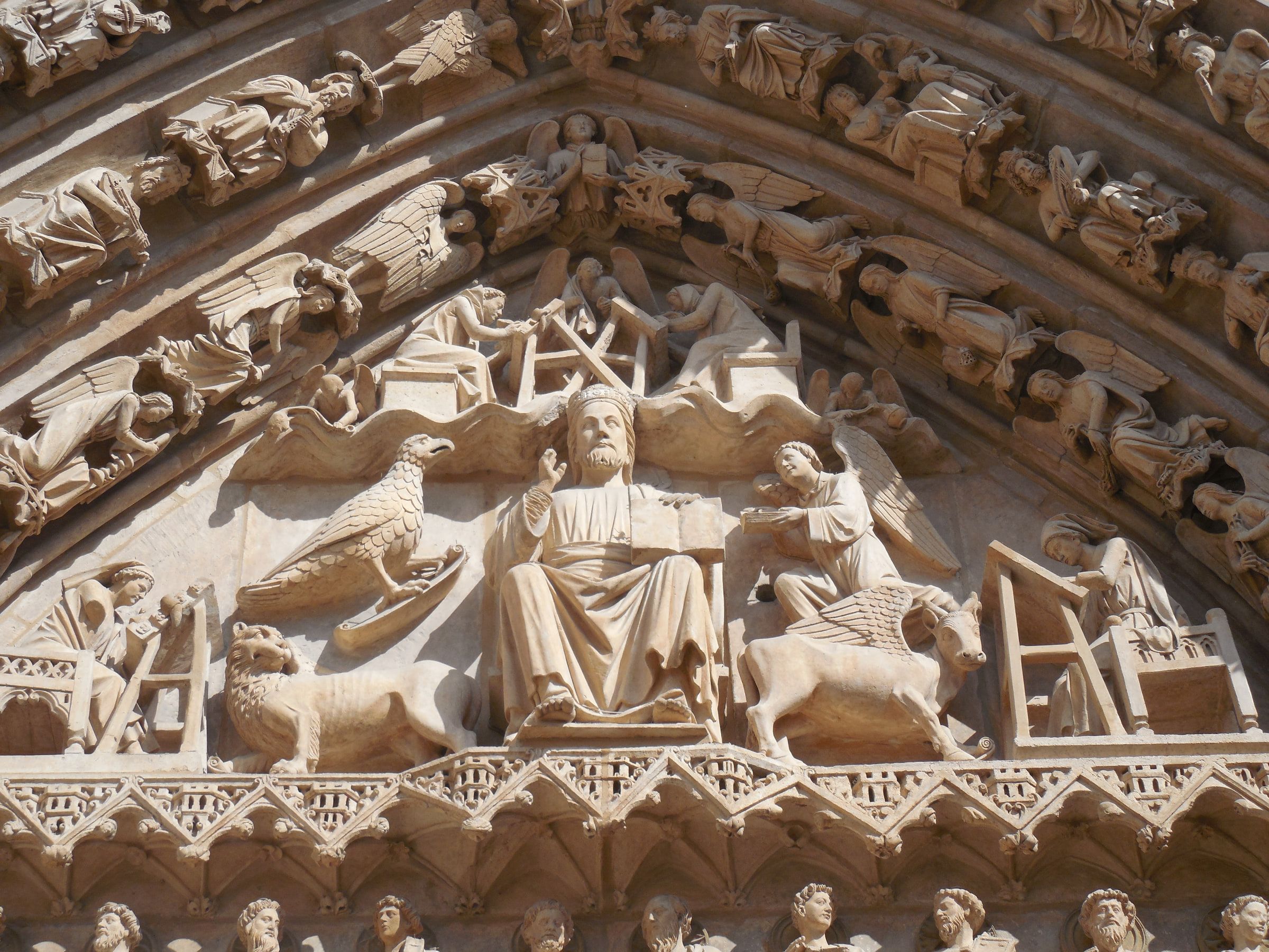 A carved tympanum with a seated central figure surrounded by winged symbols and ranks of smaller figures