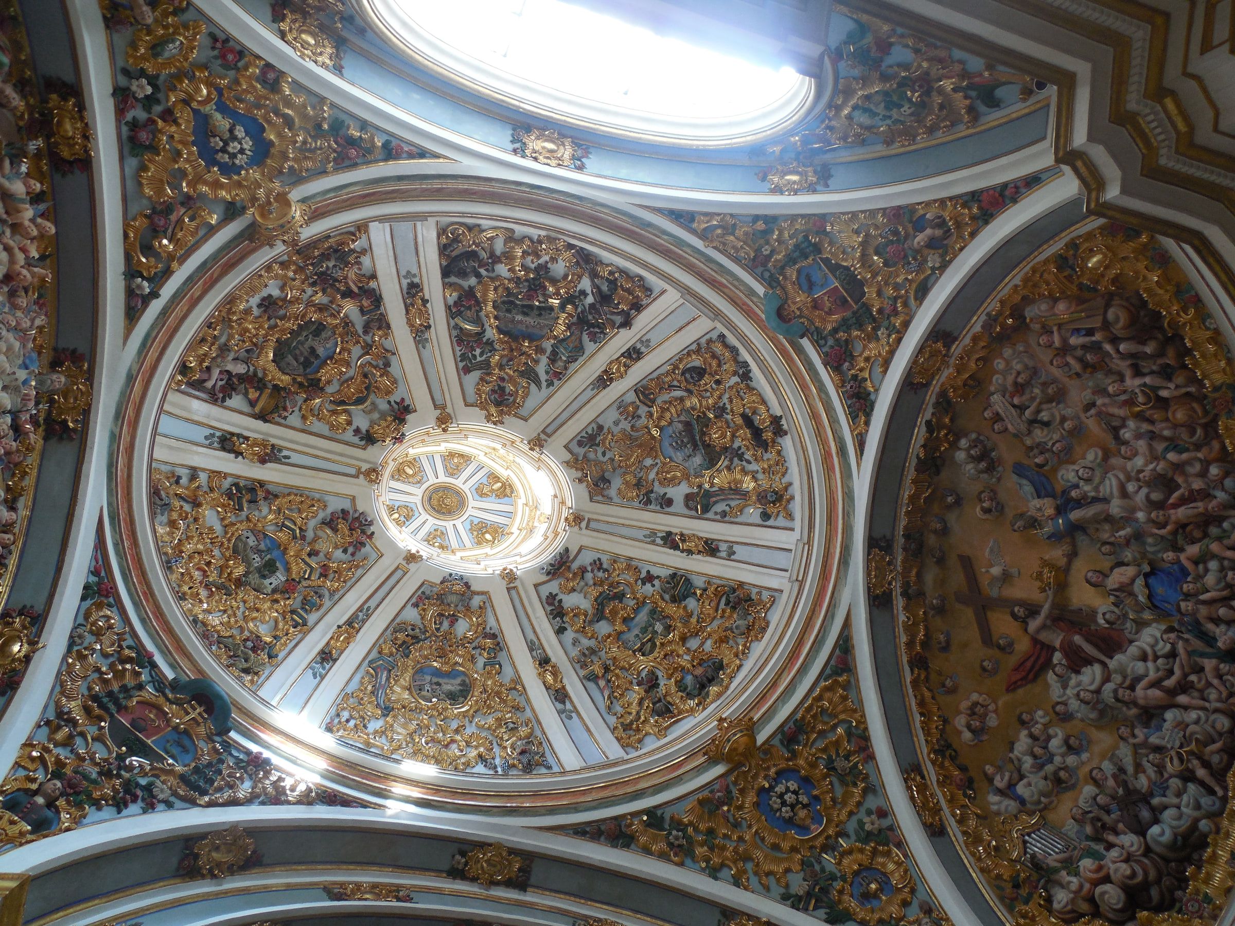 An elaborate star-shaped vault with a glazed lantern at its centre, encrusted with carved figures