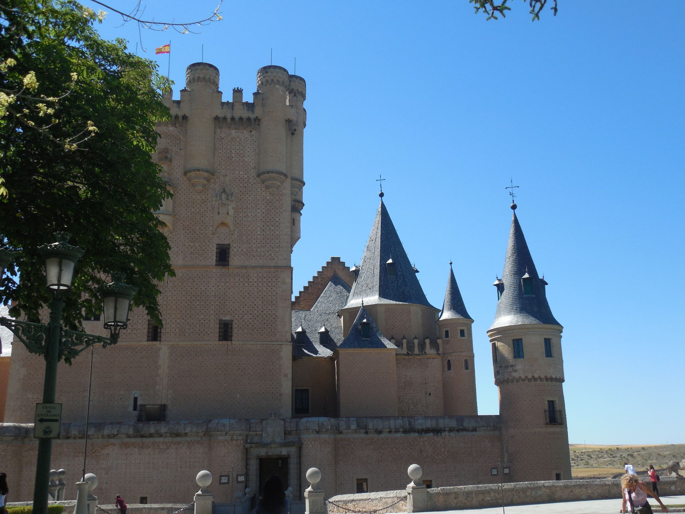 A castle of pale stone with slate-roofed turrets and a square keep, a flag flying from the top