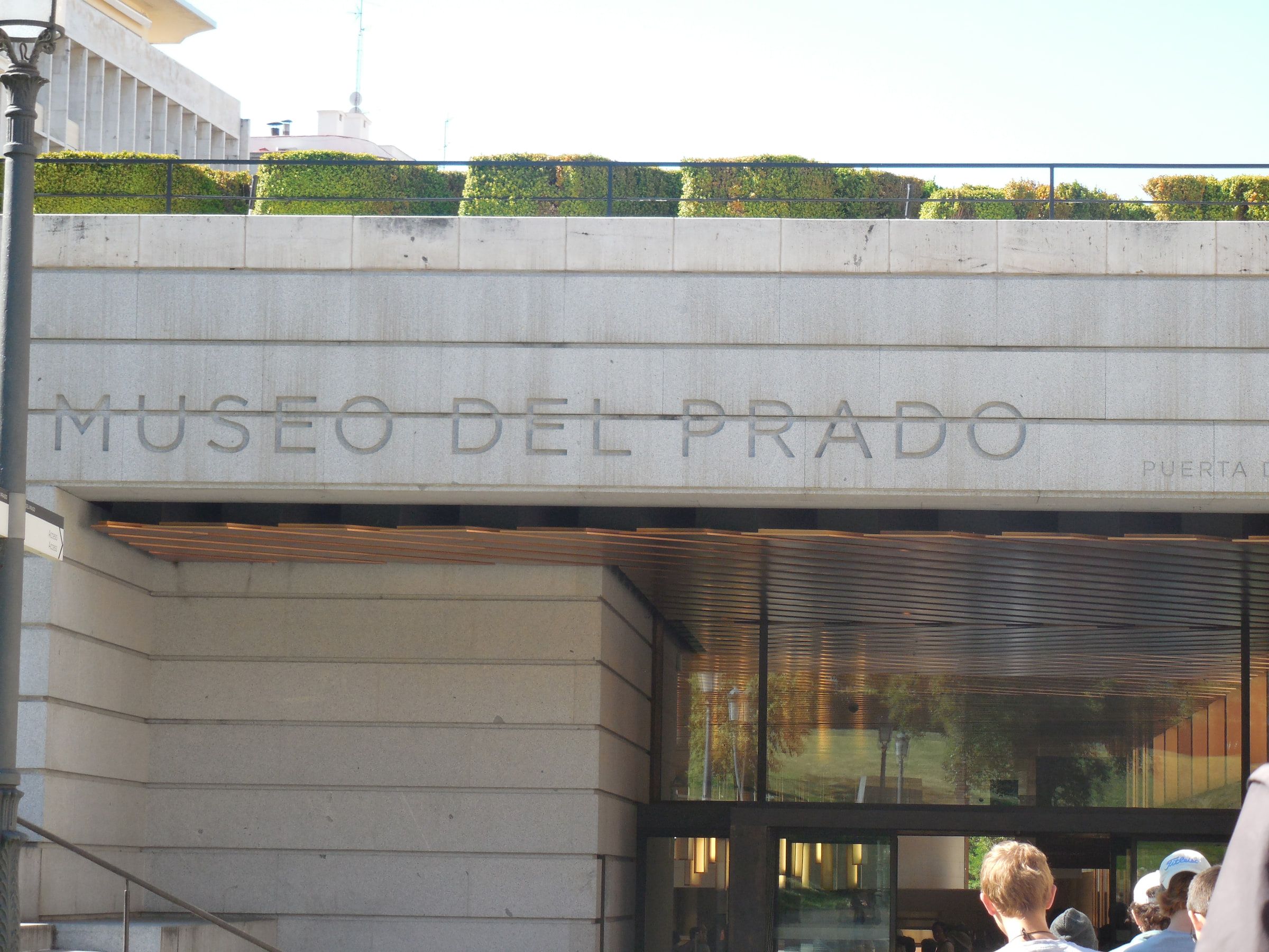 A museum entrance with the words Museo del Prado cut into the stone above glass doors