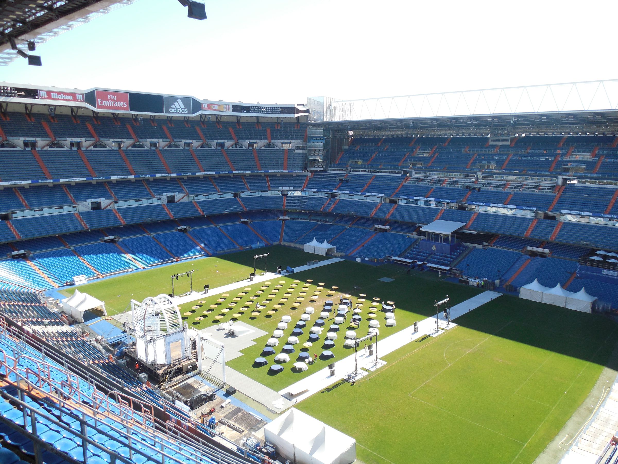 A football pitch seen from the upper tier of an empty stadium, event staging set up on the grass