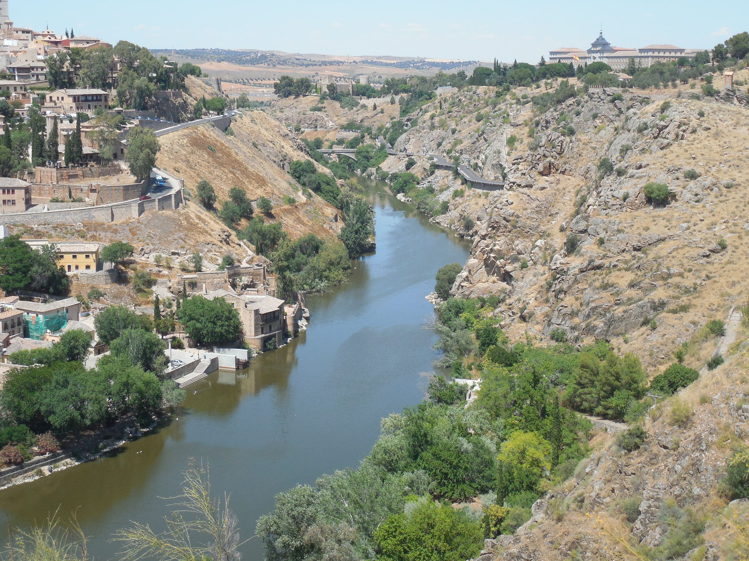 A river running through a rocky gorge below a town, a bridge and buildings on the far slope